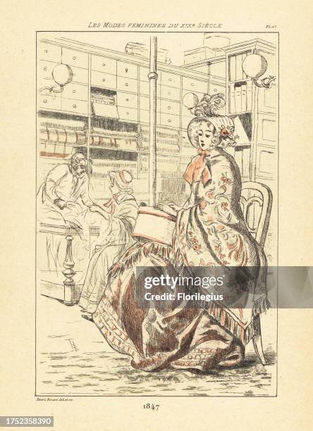 Fashionable woman with hat box sitting in a milliners, Paris, 1847. She wears a bonnet, embroidered shawl, and luxurious dress. A customer examines...