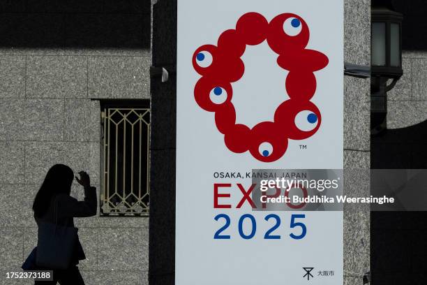 Woman walks past the logo of the Osaka Expo 2025 on October 23, 2023 in Osaka, Japan. The cost of building the Osaka Expo 2025 venue is expected to...