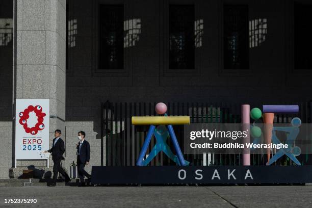 People walk past the logo of the Osaka Expo 2025 on October 23, 2023 in Osaka, Japan. The cost of building the Osaka Expo 2025 venue is expected to...