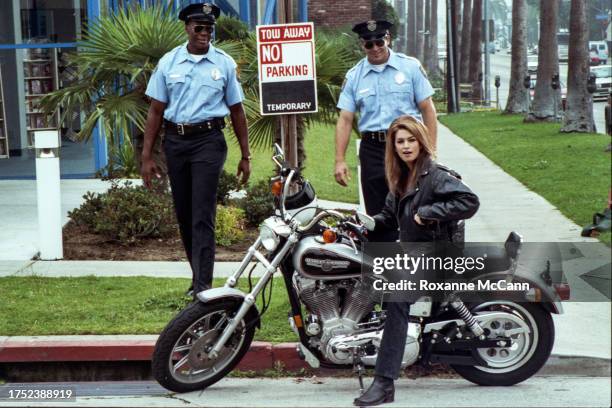 Actress and model Cindy Crawford sits on a Harley Davidson motorcycle on the set of a Pepsi commercial wearing a black leather jacket surrounded by...