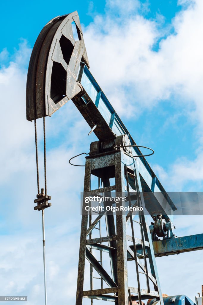Blue oil Jack pump construction working against blue sky. Low angle