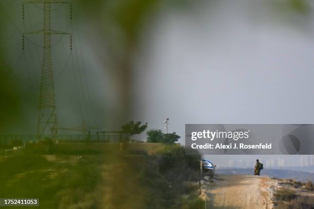 An IDF soldier walks on a hills near a waving Israeli flag on October 23, 2023 near Sderot, Israel. As Israel seems poised to invade the Gaza Strip...