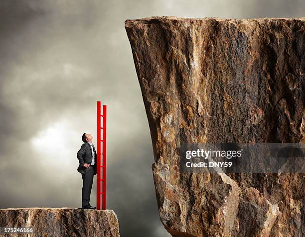 businessman holding a ladder looks up towards higher level - bridging the gap stock pictures, royalty-free photos & images