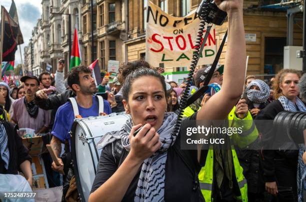 Muslim woman uses a megaphone next to a drummer and other pro-Palestinian protesters at a major demonstration against Israeli attacks on Gaza in...