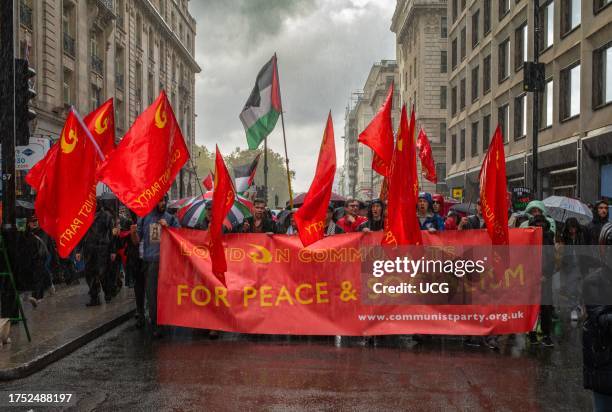 Members of the Communist Party of Britain march in the rain with red flags and thousands of pro-Palestinian protesters at a mass demonstration...