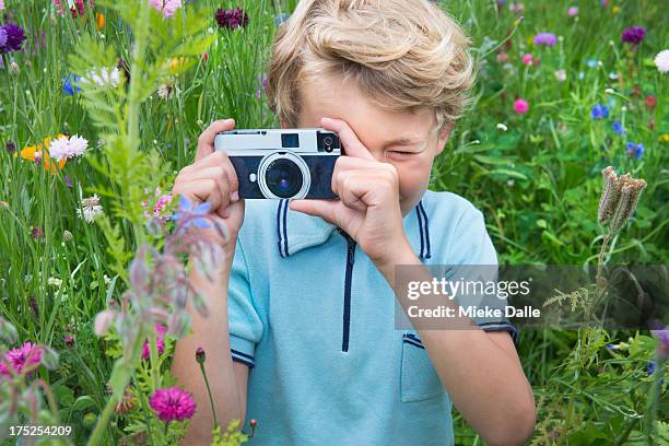 child taking a close-up picture of a wildflower - kind camera bloemen stockfoto's en -beelden
