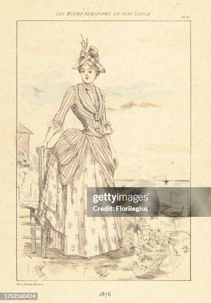 Fashionable lady standing next to a chair by the seaside, France, 1876. In hat, striped bodice and bustle skirt, floral petticoat. Handcoloured...