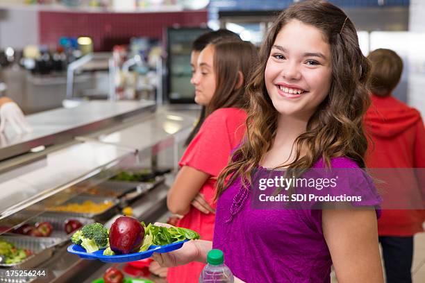 happy teenager holding her lunch at the school cafeteria - school cafeteria line stock pictures, royalty-free photos & images