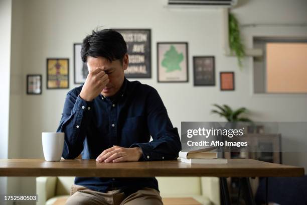 tired japanese man at home - bachelor stock pictures, royalty-free photos & images