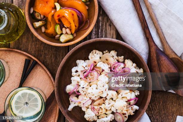 healthy vegan salads with cauliflower, orange bell pepper, white beans, zucchini, pickled red onion, table top view - roasted red onion fotografías e imágenes de stock