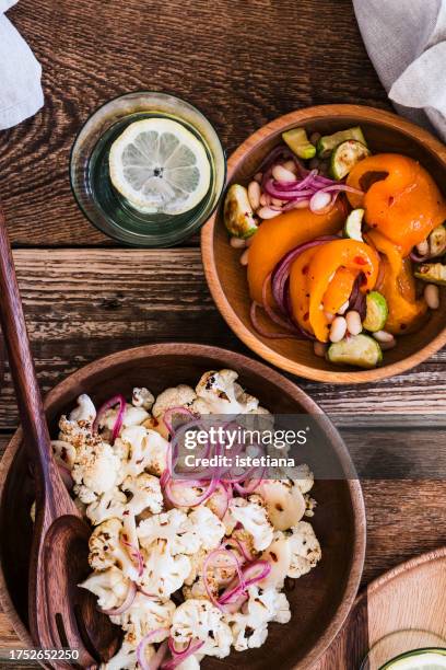 healthy vegan salads with cauliflower, orange bell pepper, white beans, zucchini, pickled red onion, table top view - violetta bell foto e immagini stock
