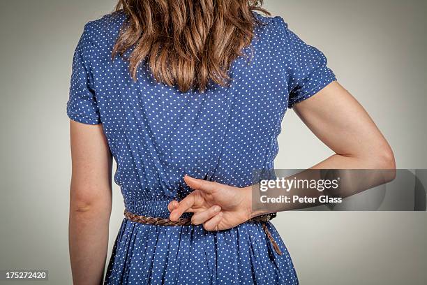 young woman crossing her fingers behind her back - mani dietro la schiena foto e immagini stock