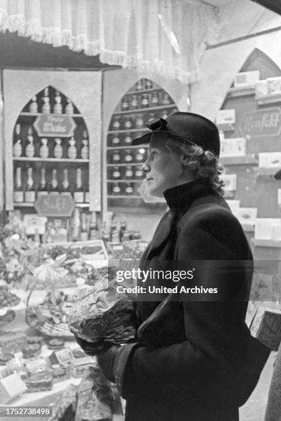 Woman doing her christmas shopping and watching a shop window, Germany 1930s.