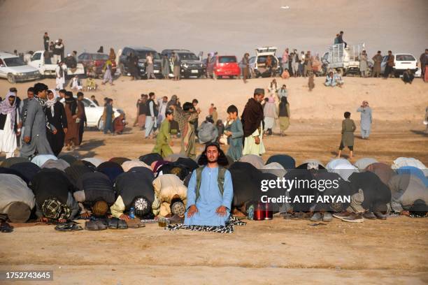 Afghan men offer prayers whilst horsemen compete during 'Buzkashi' a traditional Central Asian sport at the Dahana-i-Ghuri district of Baghlan...