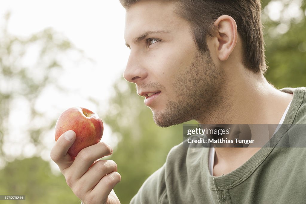 Healthy looking young man eating an apple