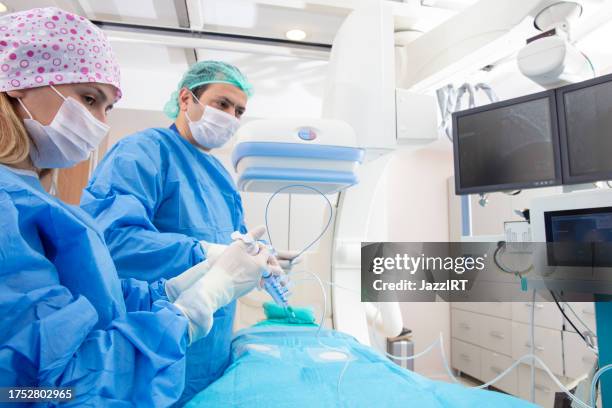 ärzteteam, das eine angiographie-operation in einem modernen krankenhaus durchführt. operationssaal. - wissenschaftliche bildtechnik stock-fotos und bilder