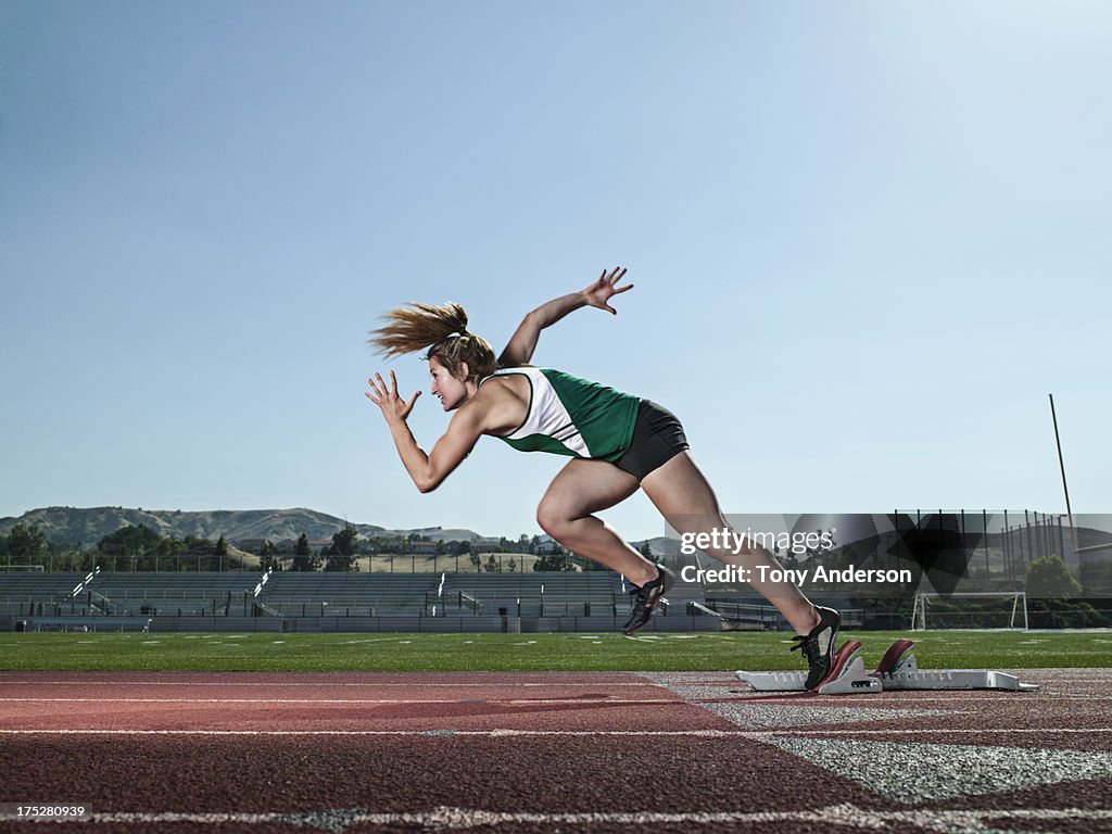 Young woman track athlete starting from blocks