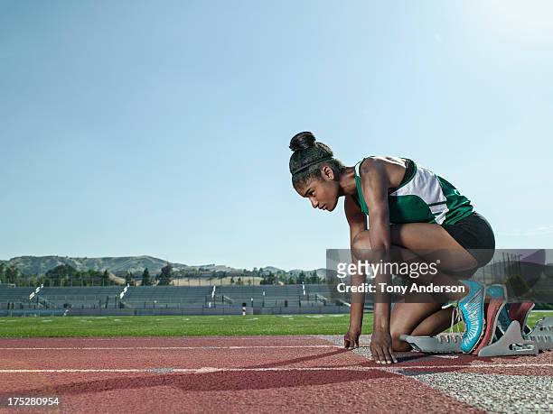 young woman track athlete at starting block - posizione sportiva foto e immagini stock