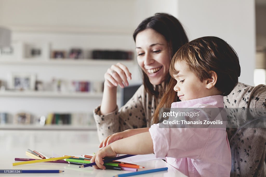 Young mother help her son with drawing