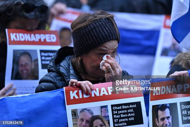 People hold up Israeli flags and posters of the missing as they gather outside the Qatari Embassy in London on October 29 to demand the release of...