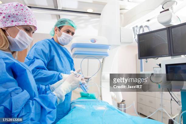 team of doctors performing angiography operation in a modern hospital. operating room. - angioplasty stock pictures, royalty-free photos & images