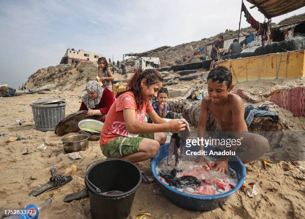 Palestinian people wash clothes with sea water due to water crisis as a result of the suspension of water flow in the water pipes from Israel to the...