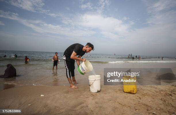 Palestinian man fills empty bottles with sea water due to water crisis as a result of the suspension of water flow in the water pipes from Israel to...