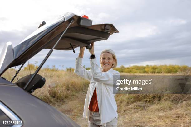 mature woman closing car trunk - car trunk closed stock pictures, royalty-free photos & images
