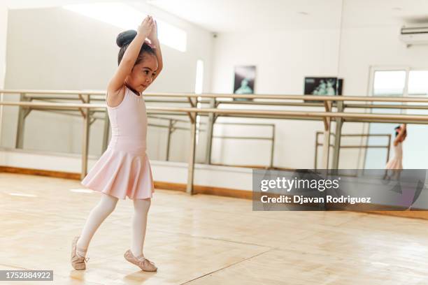 portrait of small pretty hispanic preschool pigtails ballerina dancer girl in tutu ballet dress standing smiling posing hold hands. - just dance 3 stock pictures, royalty-free photos & images