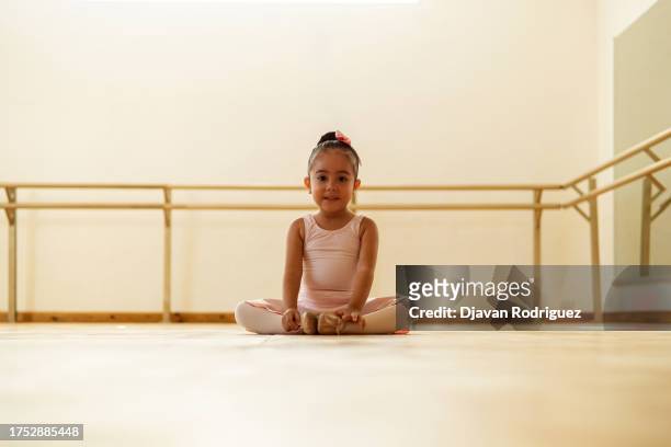 portrait of small pretty hispanic preschool pigtails ballerina dancer girl in tutu ballet dress standing smiling posing hold hands. - just dance 3 stock pictures, royalty-free photos & images
