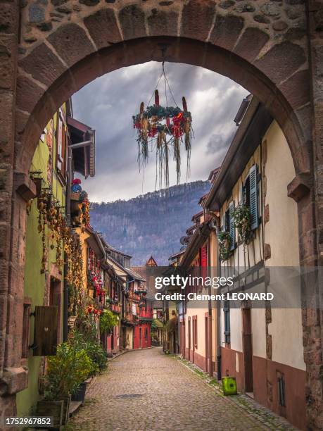 cobblestone alley with christmas decorations and colorful timber-framed houses in the medieval old town of kaysersberg, haut-rhin,  alsace, eastern france. - mercado medieval fotografías e imágenes de stock