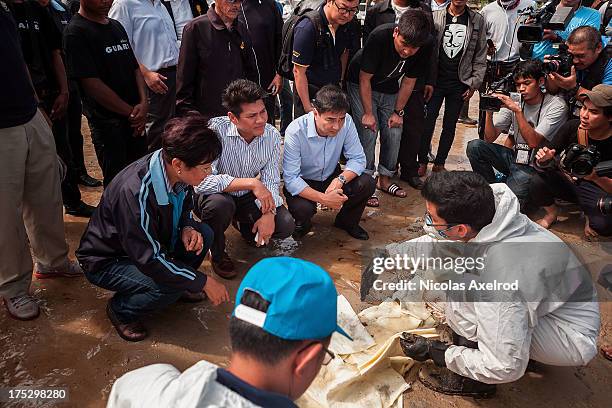 Ex-Thai Prime Minister Abhisit Vejjajiva talks to members of a team who have been tasked with the clean up of an oil spill that washed up on Koh...