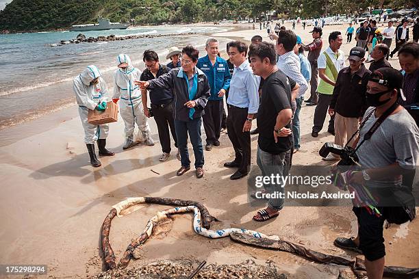 Ex-Thai Prime Minister Abhisit Vejjajiva talks to members of a team who have been tasked with the clean up of an oil spill that washed up on Koh...