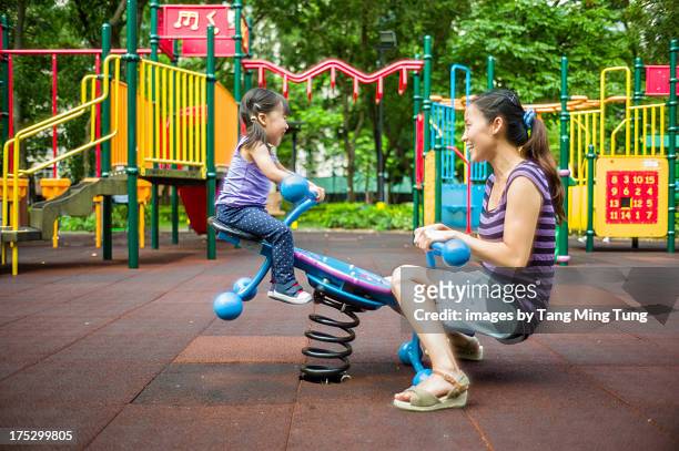 toddler girl playing seesaw with young mom - seesaw foto e immagini stock