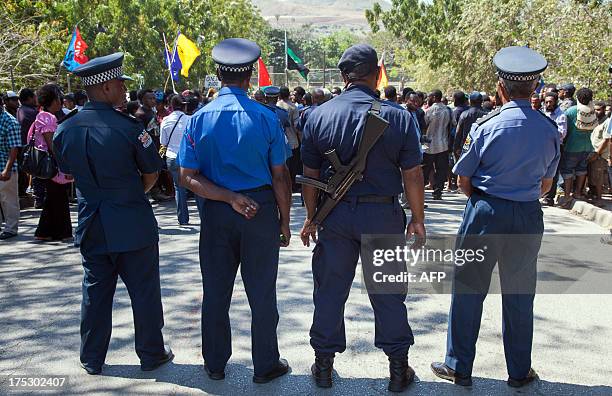 Papua New Guinea police officers watch on as hundreds of students marched towards the university gate in Port Moresby on August 2 during a protest...