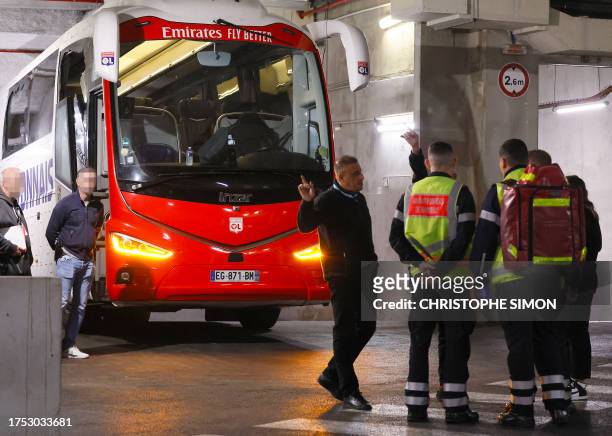 Firefighters stand next to Lyon's team bus, showing one window completely broken and another damaged, after the bus was stoned as it entered the...