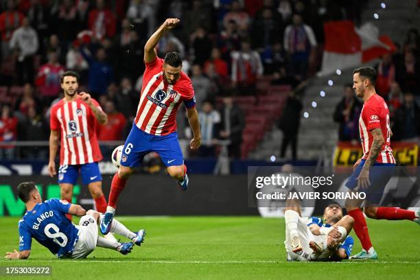 Atletico Madrid's Spanish midfielder Koke jumps over Alaves' Spanish defender Antonio Blanco during the Spanish league football match between Club...