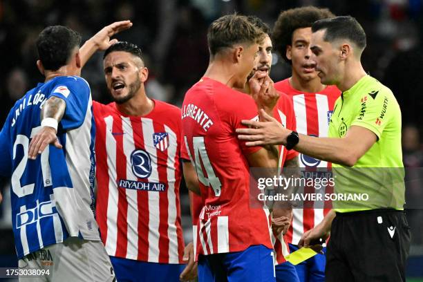 Spanish referee Muniz Ruiz talks with Atletico Madrid's Spanish midfielder Marcos Llorente after presenting him a yellow card during the Spanish...