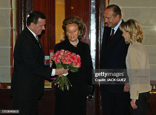 German chancellor Gerhard Schroeder offers red roses to Bernadette Chirac, as French president Jacques Chirac and the German First Lady Doris...