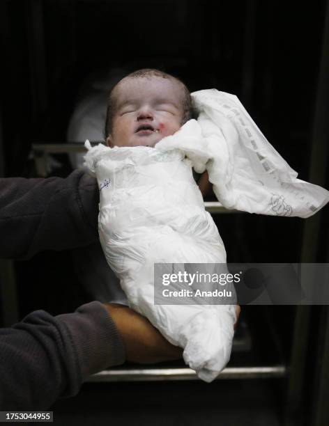 Person carries dead body of a baby who killed in Israeli attacks at Al Aqsa Martyrs Hospital as Israeli attacks continue on the 23rd day in Deir al...