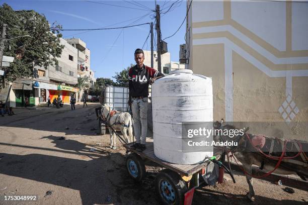 People wait in line to fill the water tank on the cart due to water crisis as a result of the suspension of water flow in the water pipes from Israel...