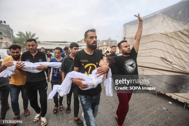 Man from the al-Aqad family holds his young nephew before the burial, who was killed in an Israeli strike on Khan Yunis in the southern Gaza Strip....
