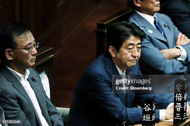 Shinzo Abe, Japan's prime minister, center, and Sadakazu Tanigaki, Japan's justice minister, left, attend a plenary session at the lower house of...