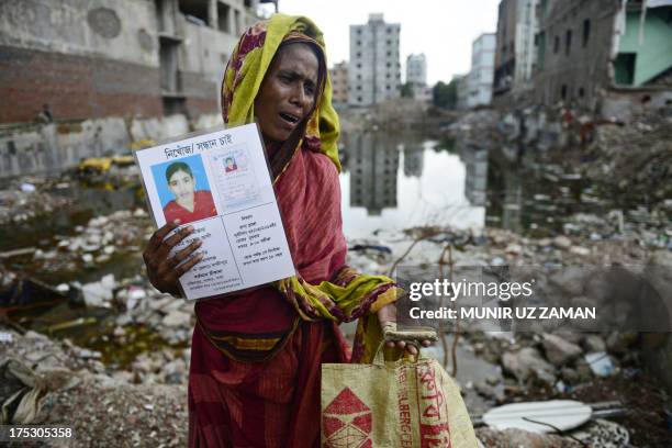 Mourner holds up a portrait of her missing relative , presumed dead following the April 24 Rana Plaza garment building collapse, and a bone fragment...