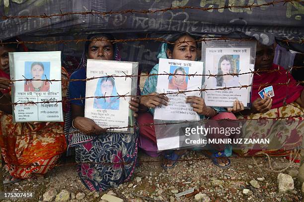 Mourners hold up portraits of their missing relatives, presumed dead following the April 24 Rana Plaza garment building collapse, at the scene during...
