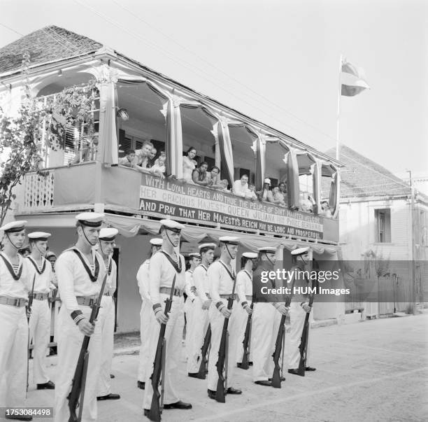 Sailors wait in Philipsburg on Sint Maarten in front of a house with a banner. The inscription reads: With loyal hearts and true the people of Sint...