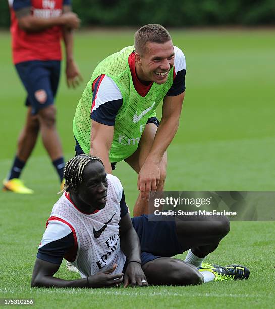 Bacary Sagna and Lukas Podolski of Arsenal joke around during a training session at London Colney on August 02, 2013 in St Albans, England.