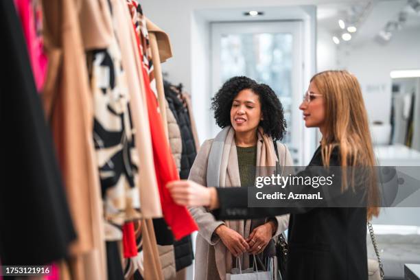 hispanic and white girlfriends buying winter clothes - small business saturday stock pictures, royalty-free photos & images