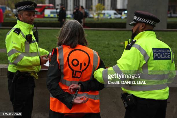 Just Stop Oil climate activist is detained by police officers after taking part in a slow march to disrupt traffic, in Parliament Square in London on...