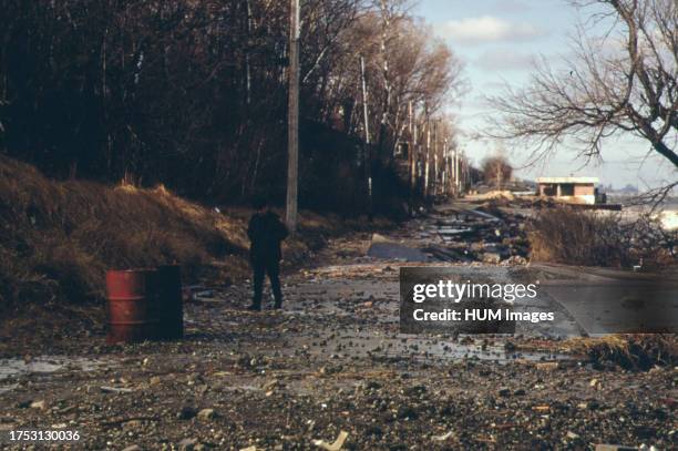 Ranger from Indiana Dunes National Lakeshore surveys Beverly Shores road washed out by severe storm on Lake Michigan ca. 1973.